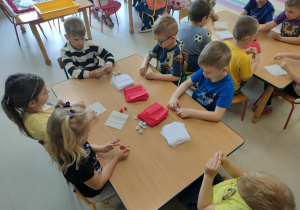Kilkoro dzieci przy stoliku formuje kulki z bibuły.
