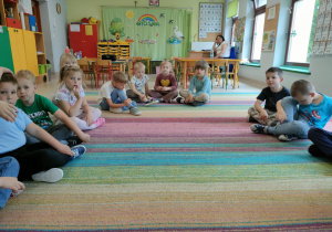 Dzieci siedzą na dywanie w kole i rozmawiają na temat treści usłyszanej bajki.