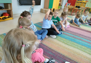 Dzieci siedzą na dywanie w kole i rozmawiają na temat treści usłyszanej bajki.