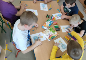 Dzieci przy drugim stole wyklejają szablon księżniczki za pomocą plasteliny.