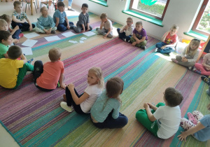 Dzieci siedzą w kole na dywanie i odpowiadają na pytania, związane z treścią bajki.