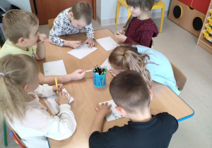 Dzieci przy stolikach rysują swojego przyjaciela/swoją przyjaciółkę.