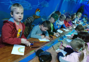 Dzieci przy połączonych stołach rysują to, co kojarzy im się z wiosną.