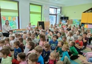 Dzieci siedzą na dywanie i słuchają dźwięków, płynących z różnych instrumentów perkusyjnych, próbując jednocześnie odgadnąć, co wydaje taki dźwięk.