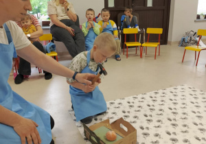 Dzieci z grupy "Motylków" podczas kolejnego doświadczenia chemicznego z wykorzystaniem mandarynki pod czujnym okiem prowadzącego.