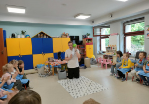 Pan Kamil prezentuje dzieciom doświadczenie z wykorzystaniem suchego lodu, butelki i balonu.