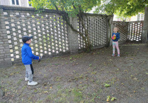 Dwoje dzieci gra w catch ball'a na ogrodzie przedszkolnym.