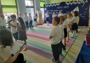 Dwoje dzieci starszych recytuje wierszyk na Uroczystości Zakończenia Przedszkola.