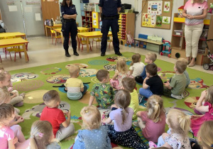 Funkcjonariusze Policji podczas prowadzenia pogadanki z dziećmi młodszymi o bezpiecznych wakacjach.