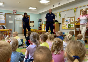 Funkcjonariusze Policji podczas prowadzenia pogadanki z dziećmi młodszymi o bezpiecznych wakacjach.