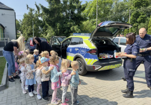 Funkcjonariusze Policji wręczają "Wiewiórkom" upominki.