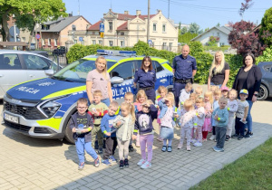 Dzieci z grupy "Wiewiórek" wraz z Funkcjonariuszami Policji na tle radiowozu.