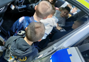 Dzieci z grupy "Pszczółek" kolejno wsiadają do radiowozu.