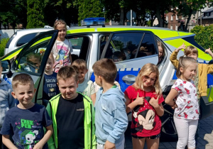 Zdjęcie dzieci z grupy "Biedronek" na tle radiowozu.
