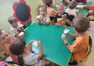 Dzieci smakują miód na wafelkach ryżowych.