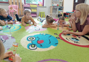Dzieci młodsze podczas ćwiczenia z kolorową klepsydrą żelową.