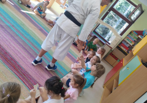 Sensei Łukasz wręcza "Pszczółkom" ulotki informacyjne, dotyczące zajęć karate.