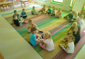 Dzieci siedzą na dywanie i odpowiadają na pytania związane z treścią listu od Profesora Animki.