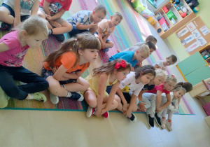 Dzieci oglądają film edukacyjny pt. "Kodeks przyjaźni z psem" na ekranie multimedialnym.