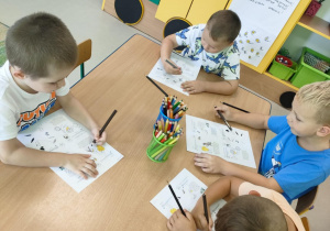 "Pszczółki" siedzą przy stoliku i rozwiązują zadania związane z programem "Psia Lekcja".