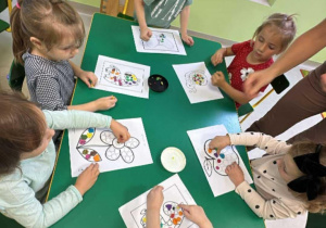 Kilkoro dzieci z grupy "Żabek" podczas kropkowanej pracy plastycznej z wykorzystaniem plasteliny.