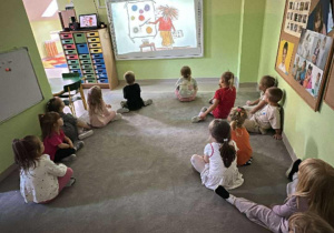 "Żabki" oglądają film edukacyjny o kropce na tablicy multimedialnej.