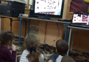 Dzieci oglądają film edukacyjny dotyczący zimowania owadów.