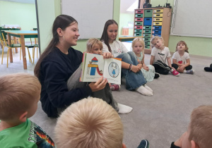 Wolontariuszka pokazuje "Żabkom" ilustrację bajki "Kicia Kocia".
