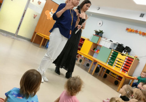 Panie prowadzące prezenetują dzieciom instrument muzyczny - flet.