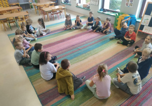 Dzieci siedzą w kole i słuchają treści listu od Profesora Animki.