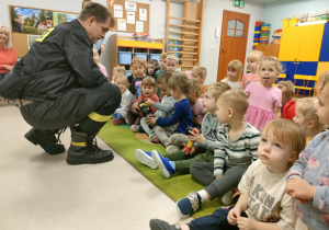 Dzieci młodsze oglądają i dotykają atrybuty strażackie.