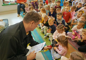 Dzieci strasze oglądają i trzymają w rączkach atrybuty strażackie.