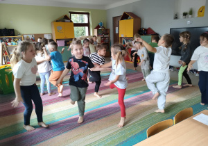Dzieci prezentują postawę bociana - ćwiczenie zaproponowane przez jedno z nich.