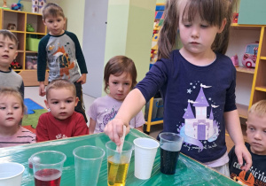 Mieszamy żółty barwnik w wodą przy wykorzystaniu patyczka.