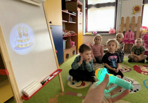 Dzieci oglądają obrazki przy użyciu mini projektora.