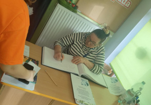 Pani Ela z Fundacji "Medor" ze Zgierza dokonuje pamiątkowego wpisu do kroniki przedszkolnej.