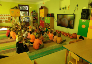 Połączone grupy "Jeżyków" i "Pszczółek" oglądają film edukacyjny o dyni na ekranie multimedialnym.