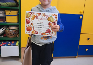 Chłopiec z naszego przedszkola z dyplomem oraz nagrodą za zdobycie wyróżnienia w konkursie fotograficznym "Moja jesienna wyprawa".