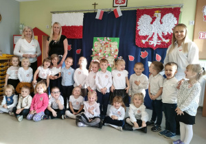 Dzieci z grupy "Wiewiórek" na tle patriotycznej dekoracji.