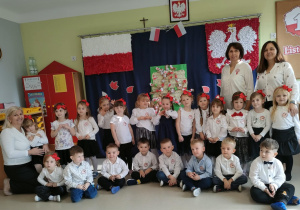 Dzieci z grupy "Żabek" na tle patriotycznej dekoracji.