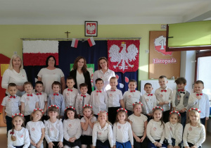 Dzieci z grupy "Pszczółek" na tle patriotycznej dekoracji.