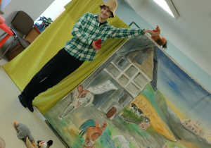 Farmer Szymon układa maskotki przy pojemniku z ziarenkami.