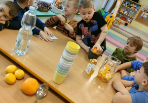 Chłopcy po kolei wyciskają sok, przy użyciu ręcznej wyciskarki.