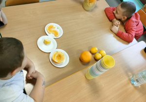 Chłopcy mieszają wodę z miodem, cytryną i pomarańczą w dzbanku.