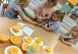 Dziewczynki po kolei wyciskają sok, przy użyciu ręcznej wyciskarki.