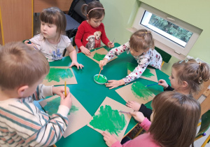 Dzieci malują tekturę na zielono.