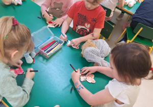 Dzieci z grupy "Żabek" kolorują drewniane misie, przy pomocy mazaków.