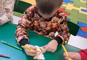 Dzieci z grupy "Żabek" kolorują drewniane misie, przy pomocy mazaków.