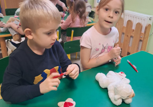 Dzieci z grupy "Żabek" kolorują drewniane misie, przy pomocy mazaków.