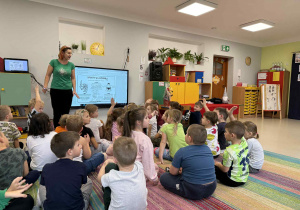 Dzieci siedzą na dywanie i rozmawiają na temat japońskich sportów.